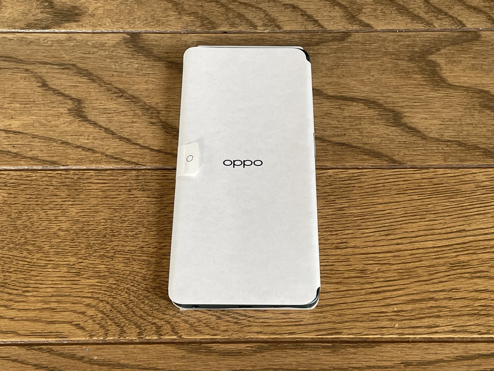 OPPO A5 5Gを箱から取り出した直後の保護紙に包まれたスマートフォン本体