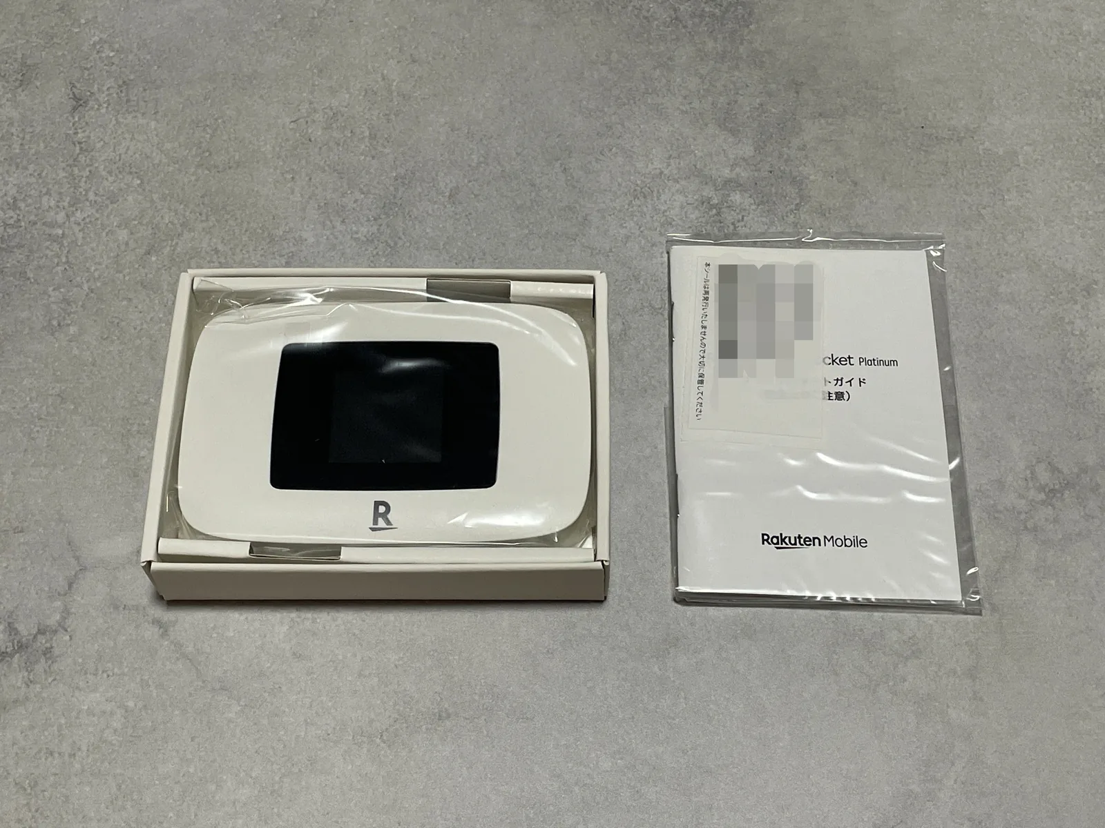 Rakuten WiFi Pocket Platinumを開封し、モバイルルーター本体と付属書類を確認している様子
