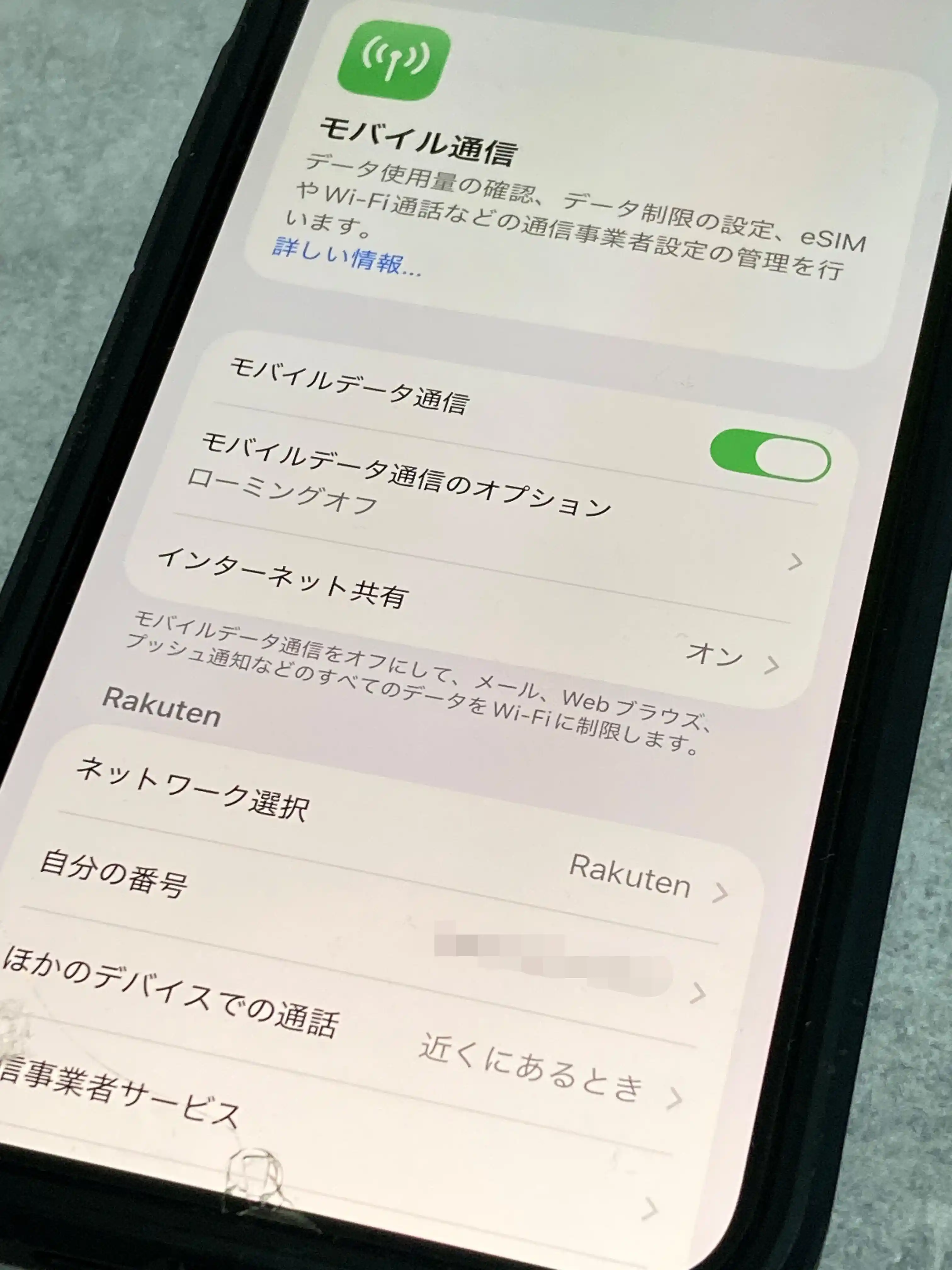 iPhoneの設定アプリのモバイル通信画面。ネットワーク選択に「Rakuten」と表示されている(電話番号は加工済み)をスマホで撮影した写真